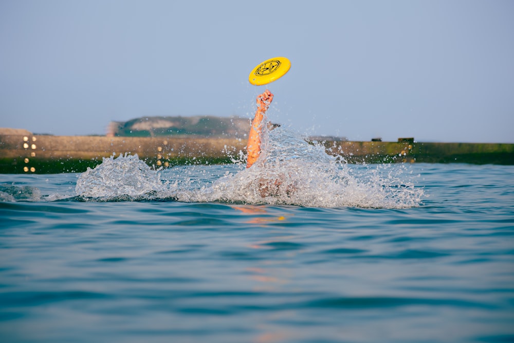 a person jumping into the water to catch a frisbee