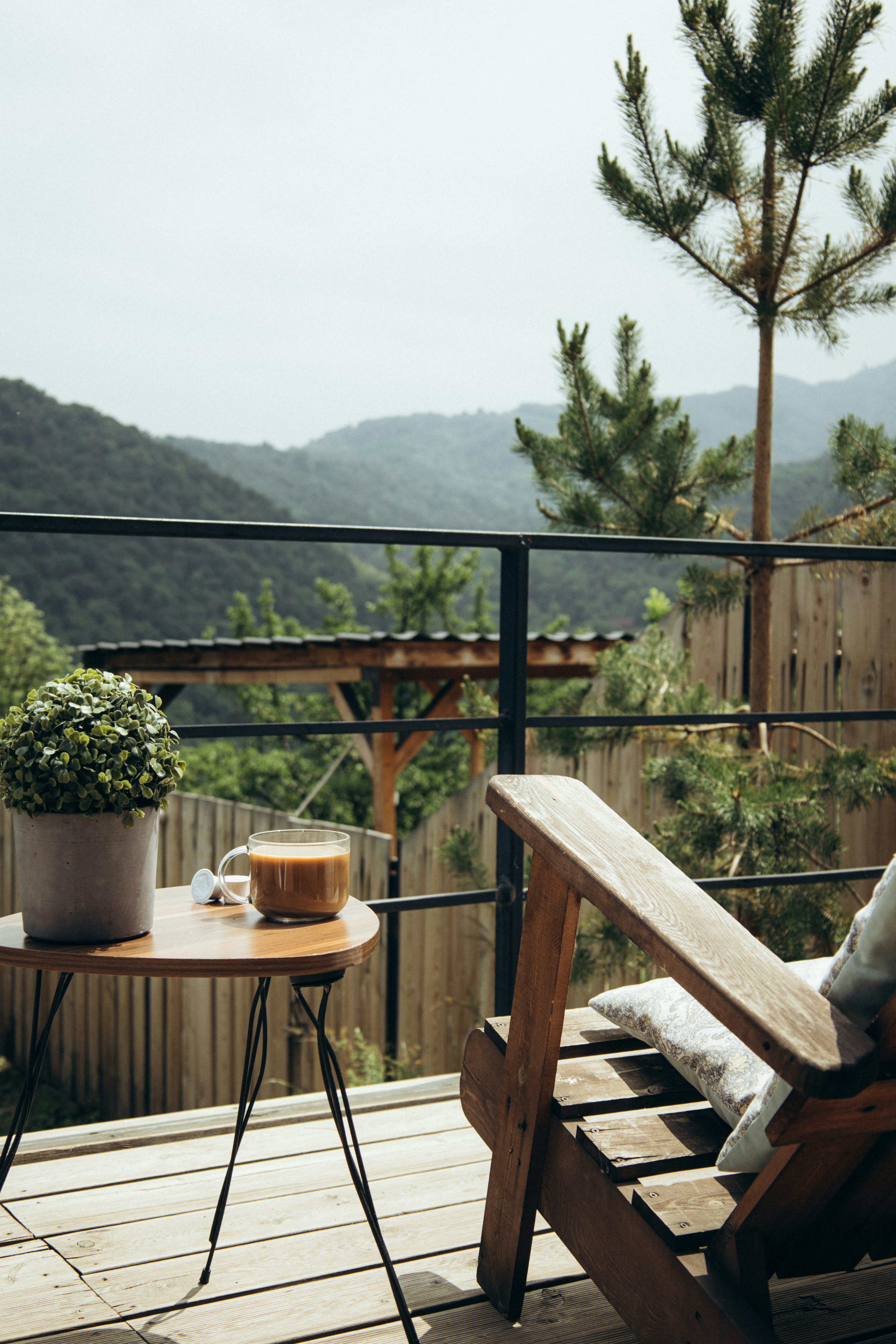 Round table with coffee and plant on a balcony with mountain view.