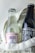 Two glass bottles of Indi & Co organic beverages are placed side by side in a cream-colored textile basket. One bottle appears clear with a strawberry label, while the other is dark with a kola soda label.