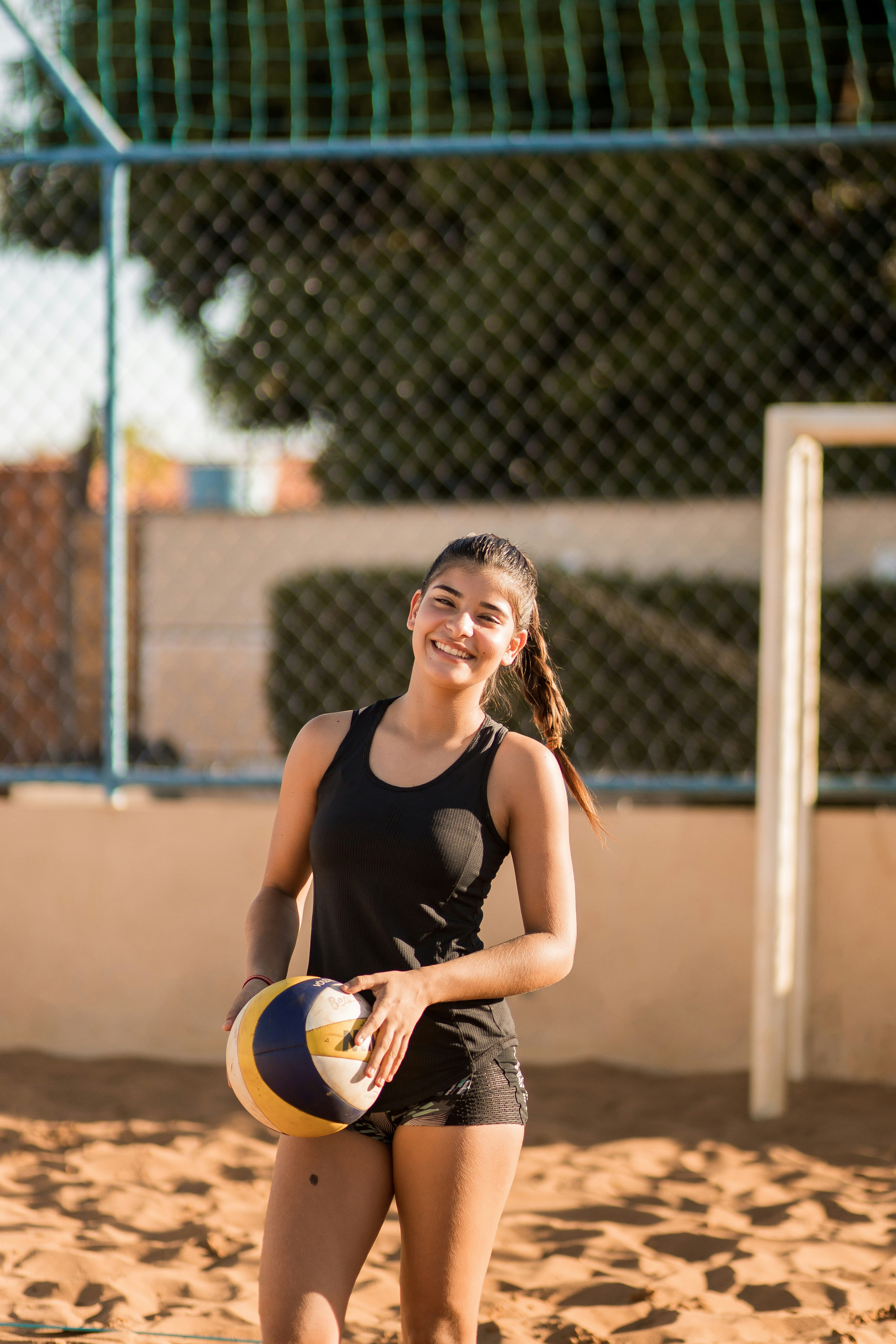 Una mujer sosteniendo una pelota de voleibol en una playa foto – Imagen ...