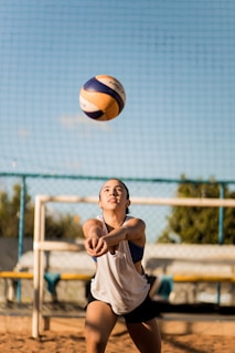 a woman reaching up to hit a volleyball