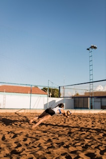 a man diving for a frisbee on a sandy beach