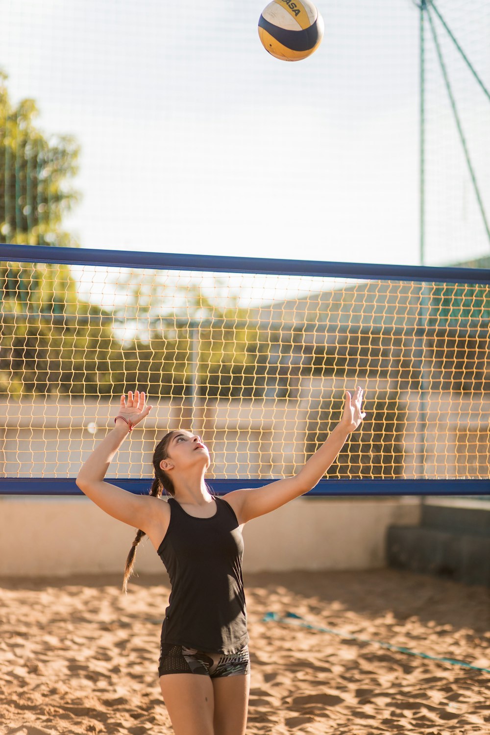 a woman reaching up to hit a volleyball
