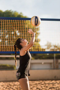 a woman reaching up to hit a volleyball