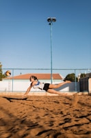 A close-up of a volleyball player diving to save the ball on a sandy court.