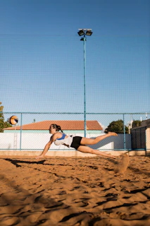 Close-up of a joyful player diving to save the ball on a sandy court.