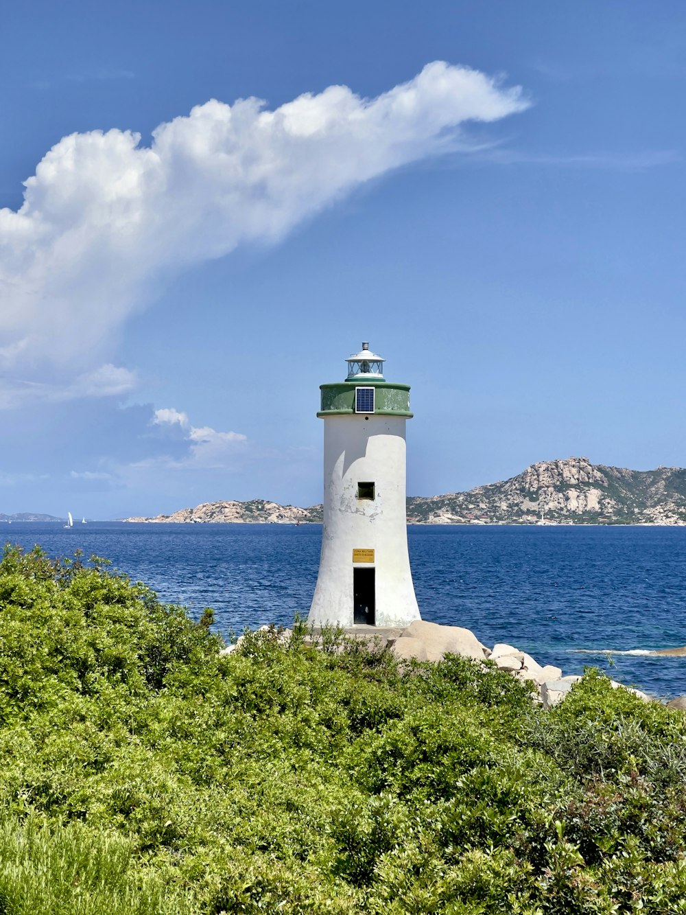 a white lighthouse sitting on top of a lush green hillside