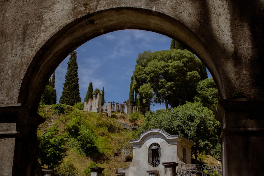 an arch in a stone building with trees on a hill in the background