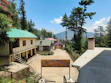 Smiling parent standing with their child in front of the lush green 13-acre Nubra High School campus.