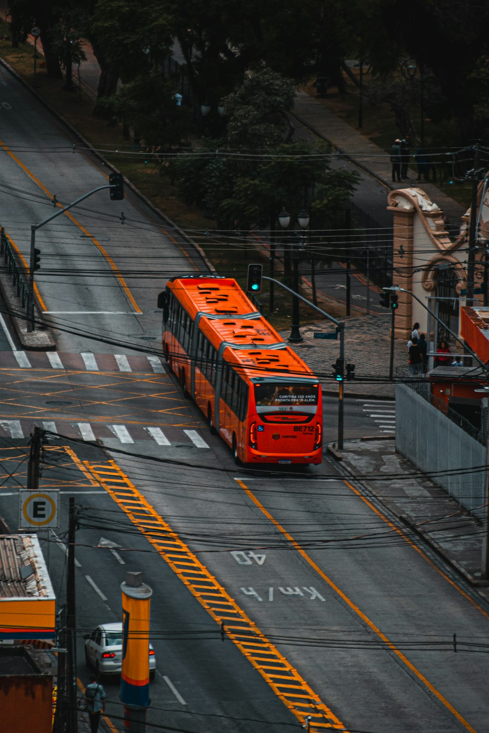 a red bus driving down a street next to a traffic light