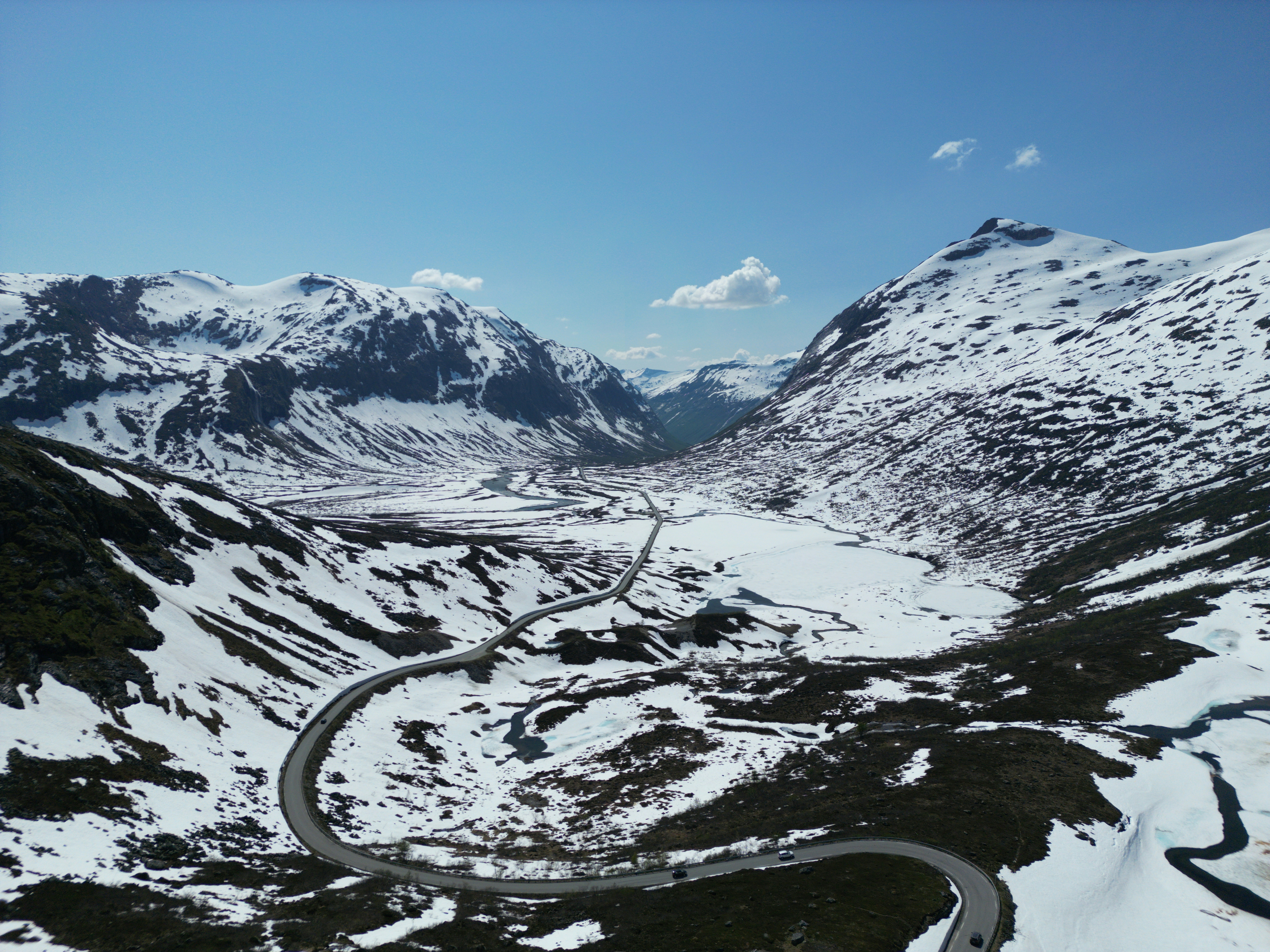 a winding road surrounded by snow covered mountains