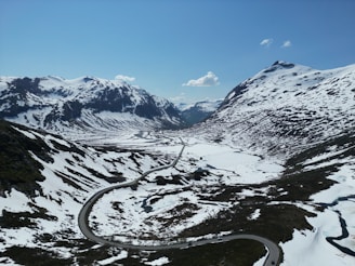 a winding road surrounded by snow covered mountains