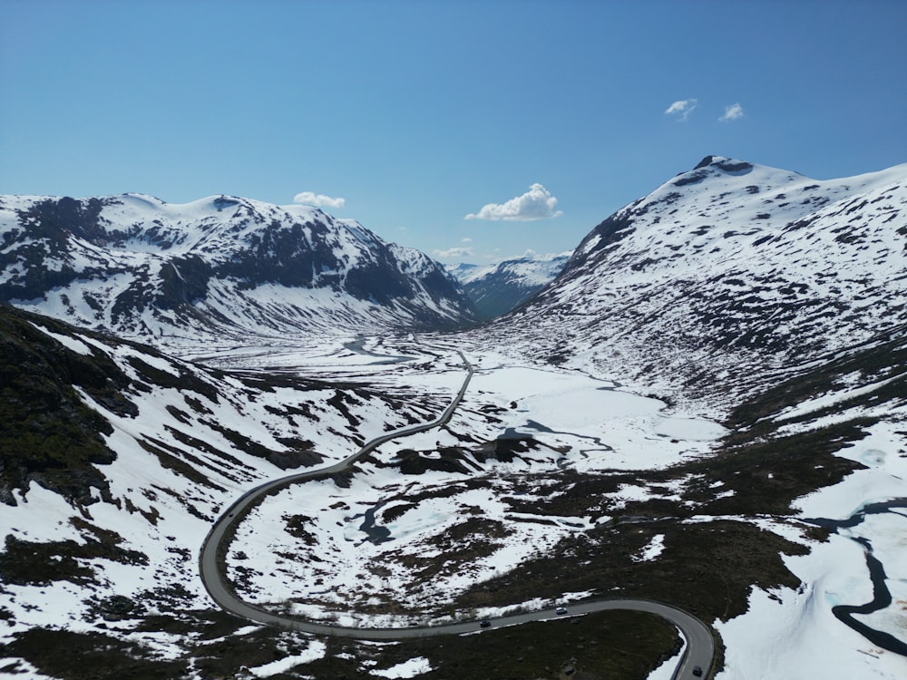 a winding road surrounded by snow covered mountains