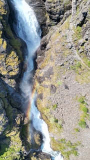Lush aerial view of Iguazu Falls with colorful rainbows arching over cascading water.