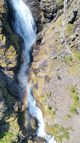 Lush aerial view of Iguazu Falls with colorful rainbows arching over cascading water.