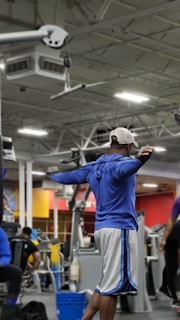 Exercise physiologist demonstrating proper stretching techniques in an urban-style gym space.