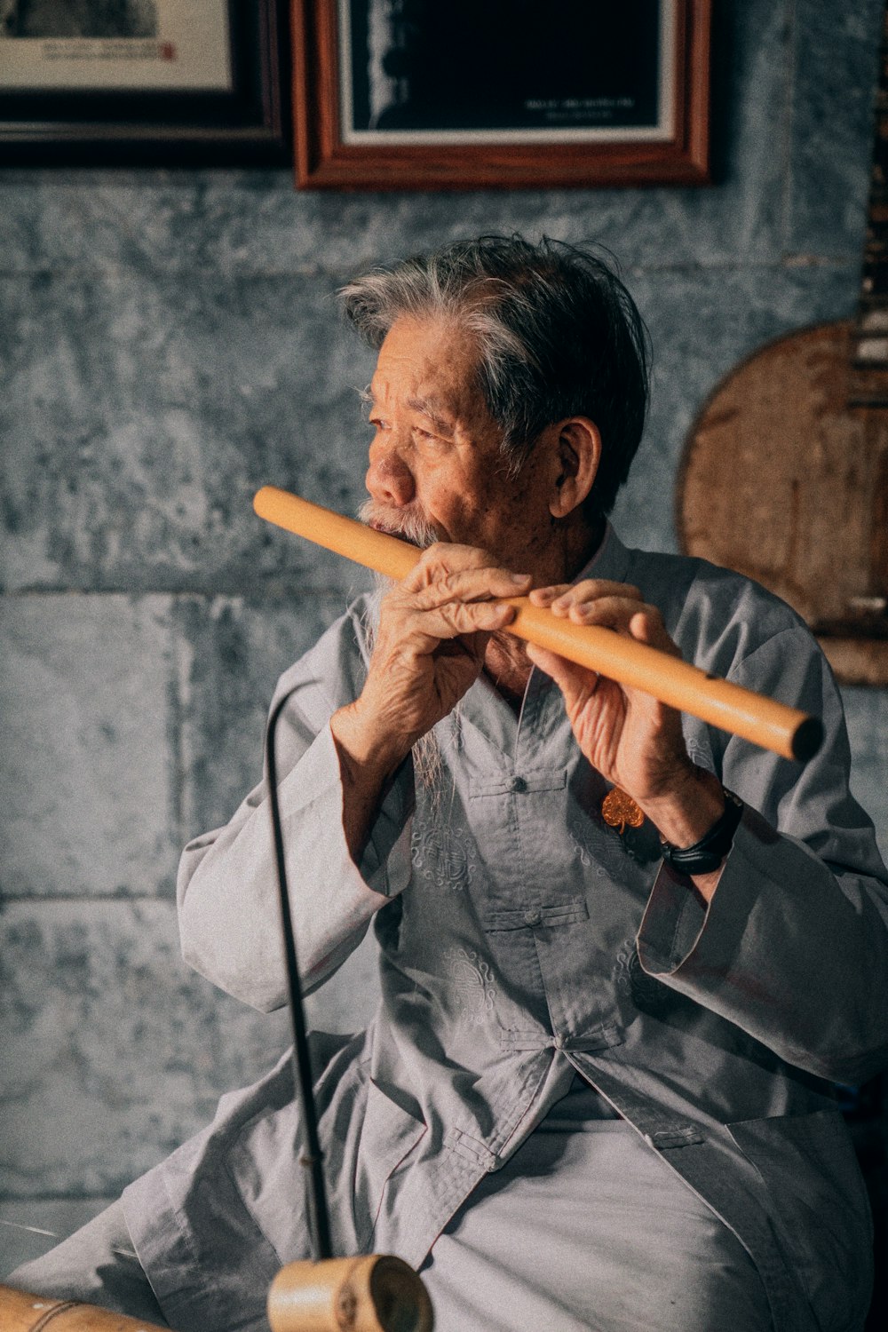 a man sitting on a chair playing a flute