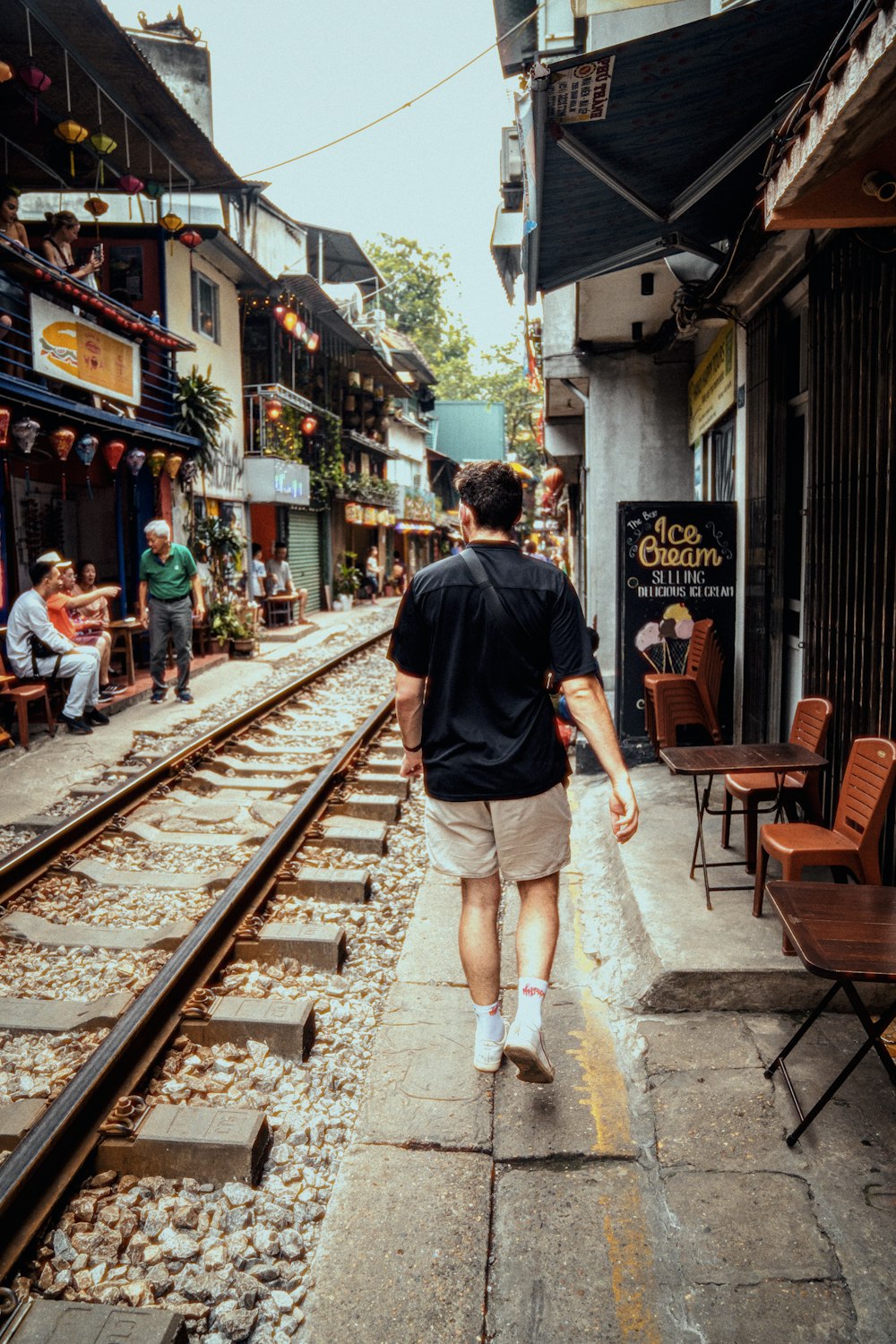 a man walking down a street next to train tracks