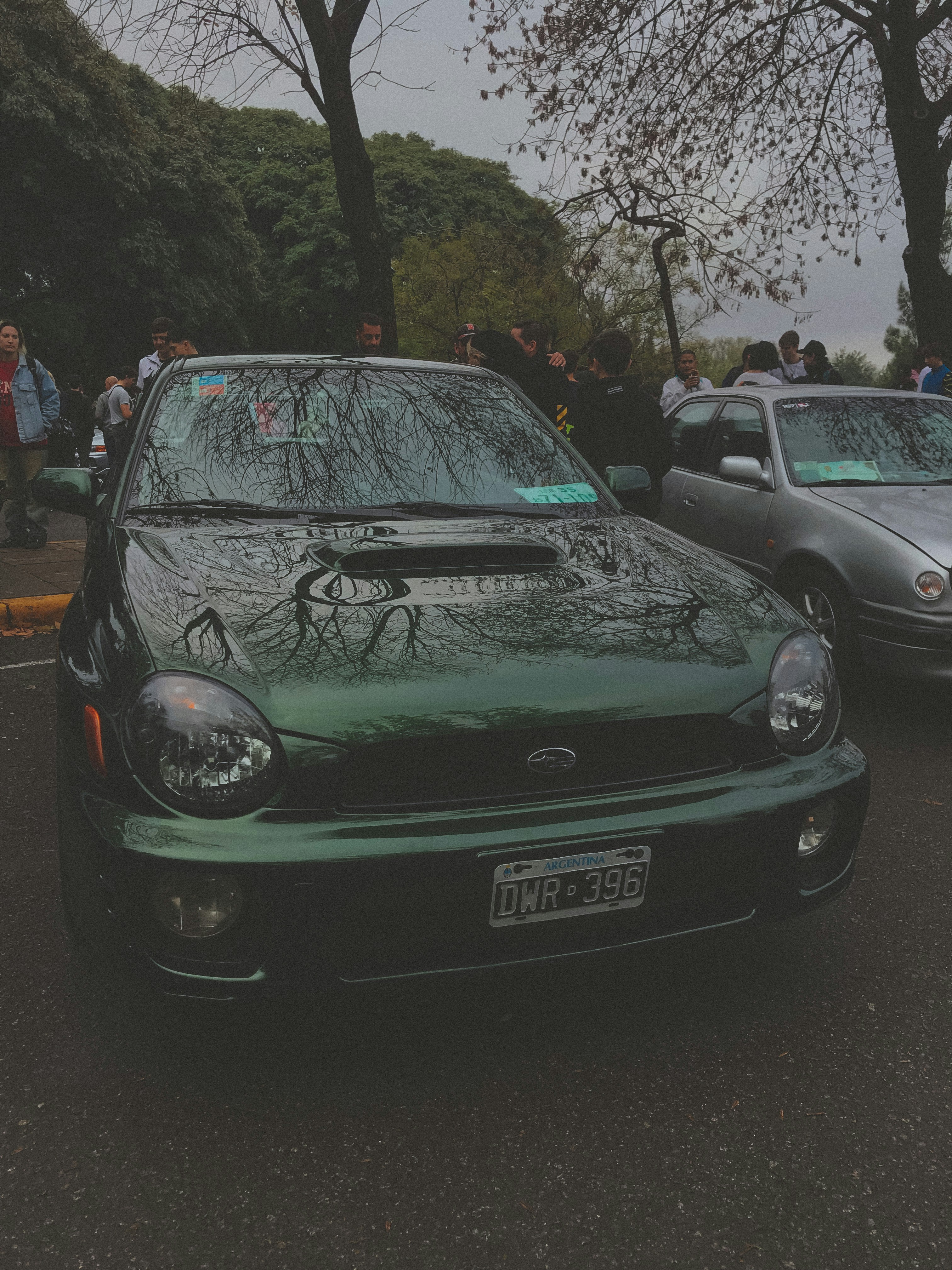 ein grünes Auto, das auf einem Parkplatz neben anderen Autos geparkt ist