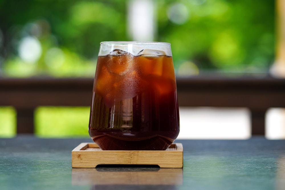 un verre de soda posé sur un plateau en bois