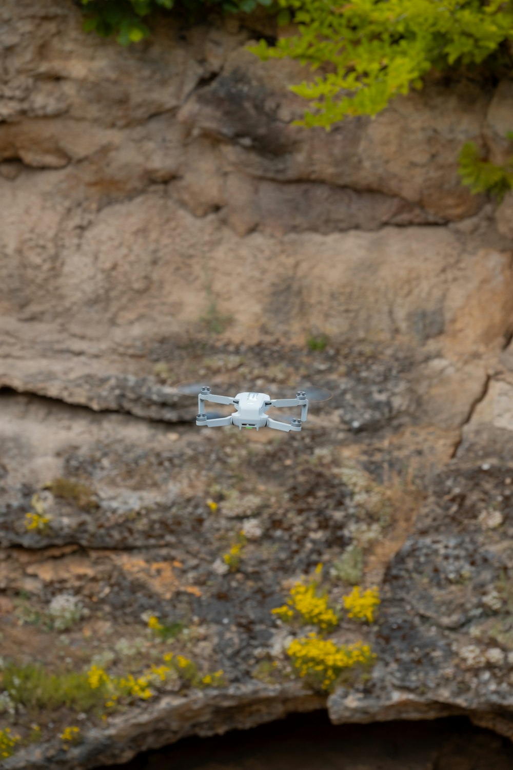 a small white object flying over a rocky cliff