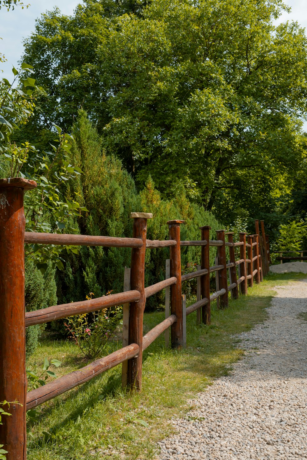 une clôture en bois est à côté d’un chemin de gravier