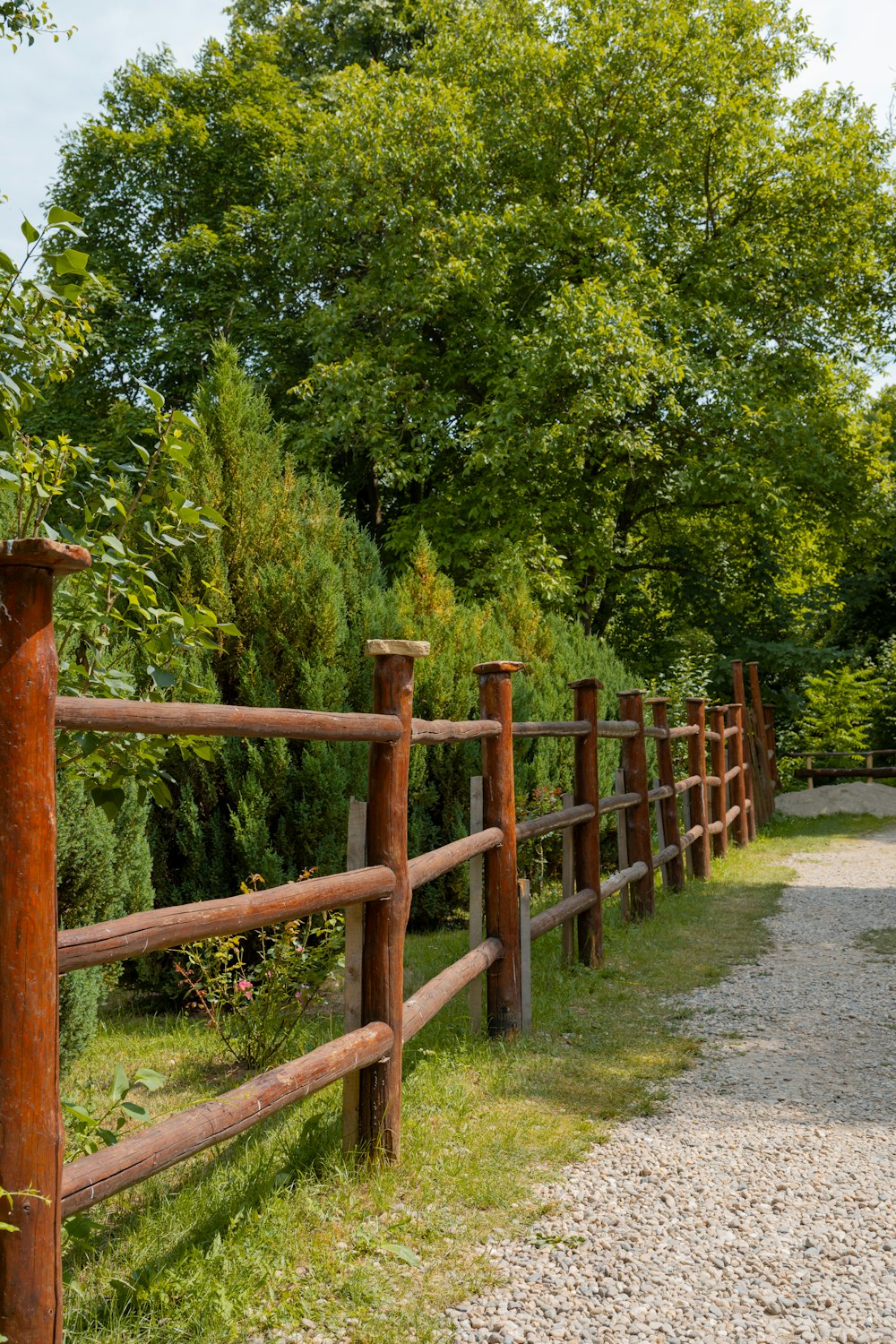 une clôture en bois est à côté d’un chemin de gravier