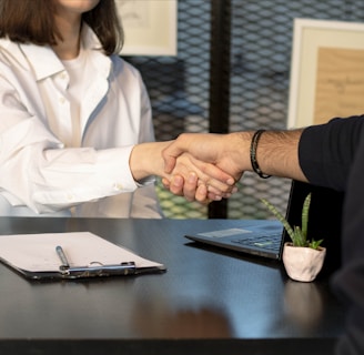 a man and a woman shaking hands in front of a laptop