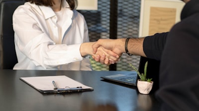 a man and a woman shaking hands in front of a laptop