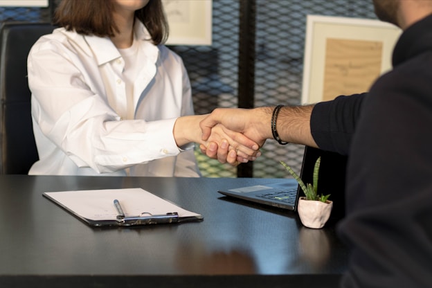 a man and a woman shaking hands in front of a laptop