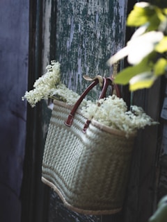 Crochet bag hanging from a vintage bike basket on a sunny day surrounded by flowers