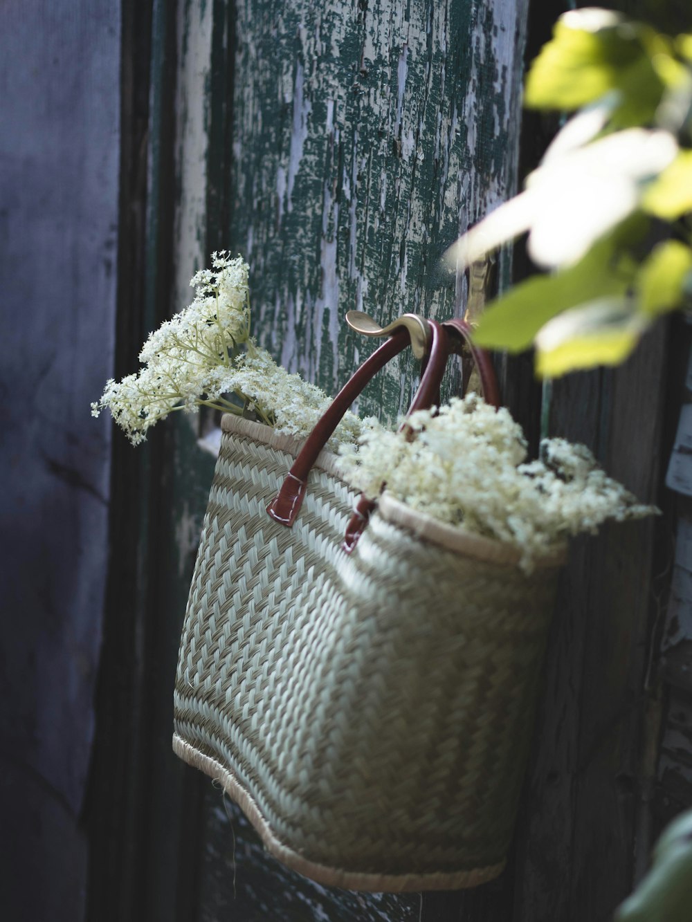 a basket hanging from a door with flowers in it