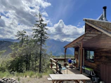 A peaceful morning view of a cabin porch with comfortable chairs and nature surrounding it.