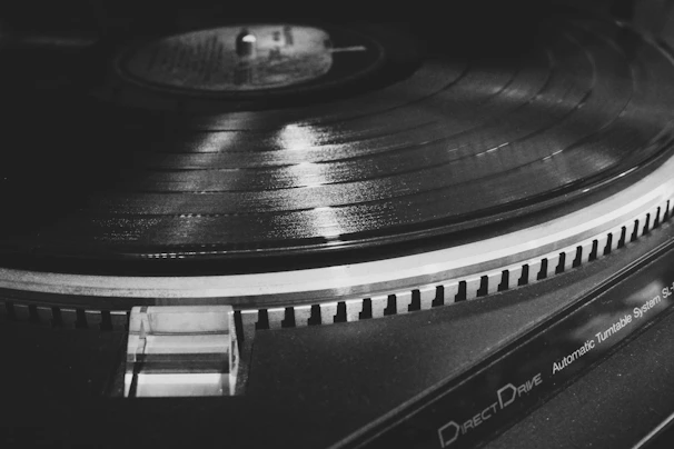 Black and white shot of a vinyl record spinning, emphasizing texture and detail.