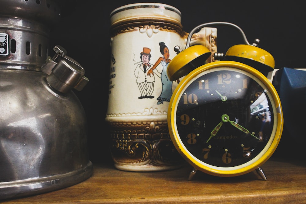 a yellow alarm clock sitting on top of a wooden table