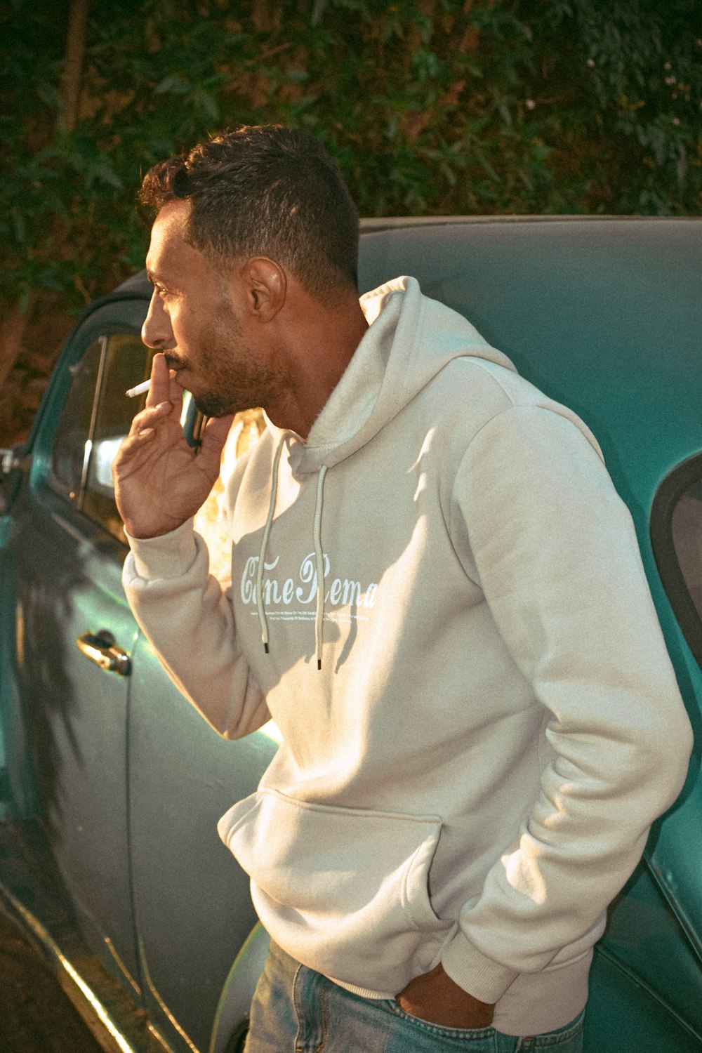 a man standing next to a car talking on a cell phone