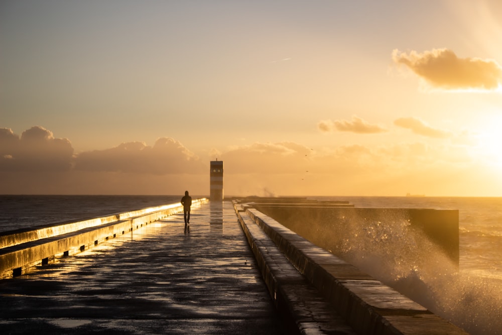 a person standing on a pier near the ocean