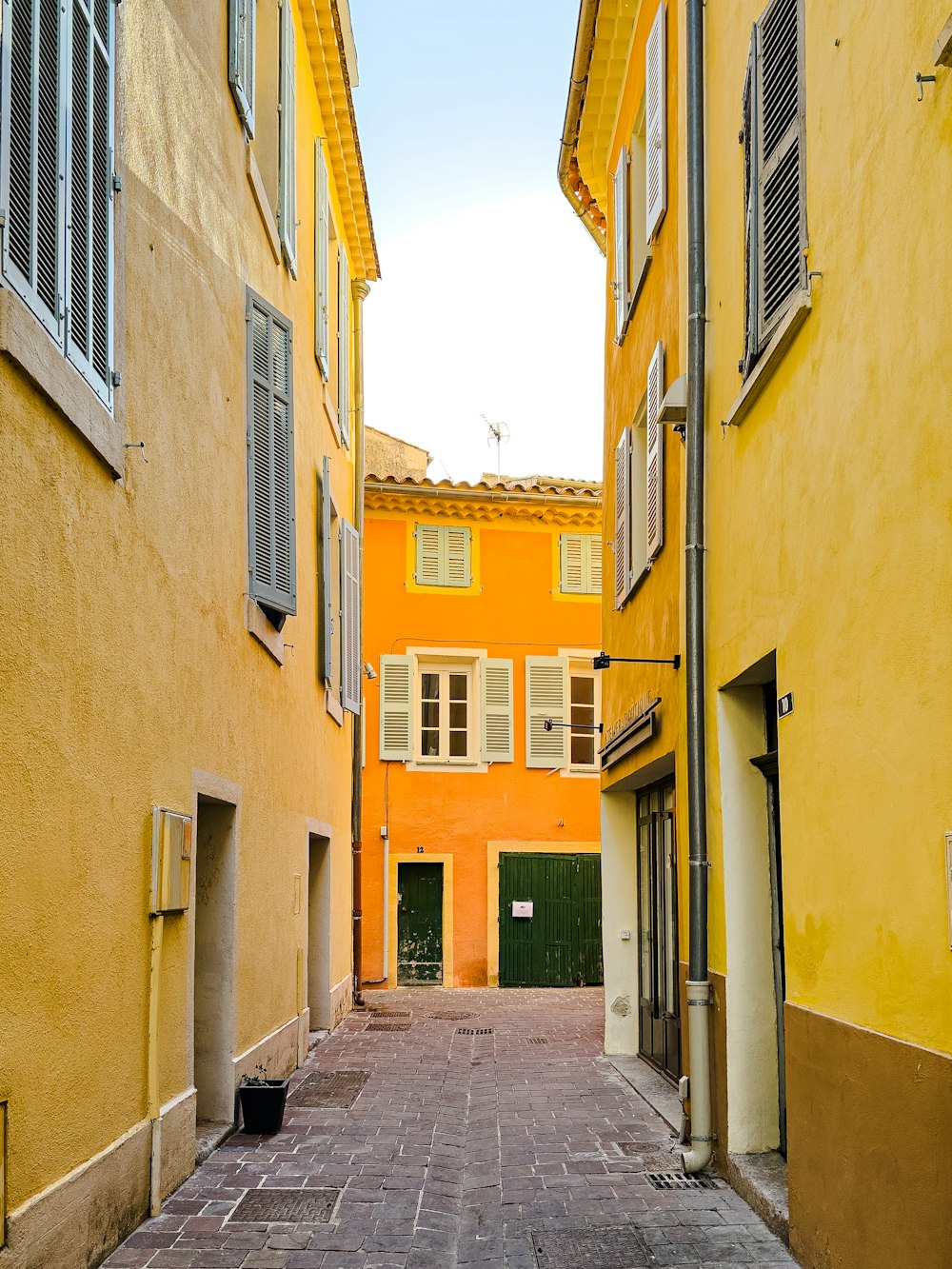 eine schmale Gasse mit gelben Gebäuden und Fensterläden