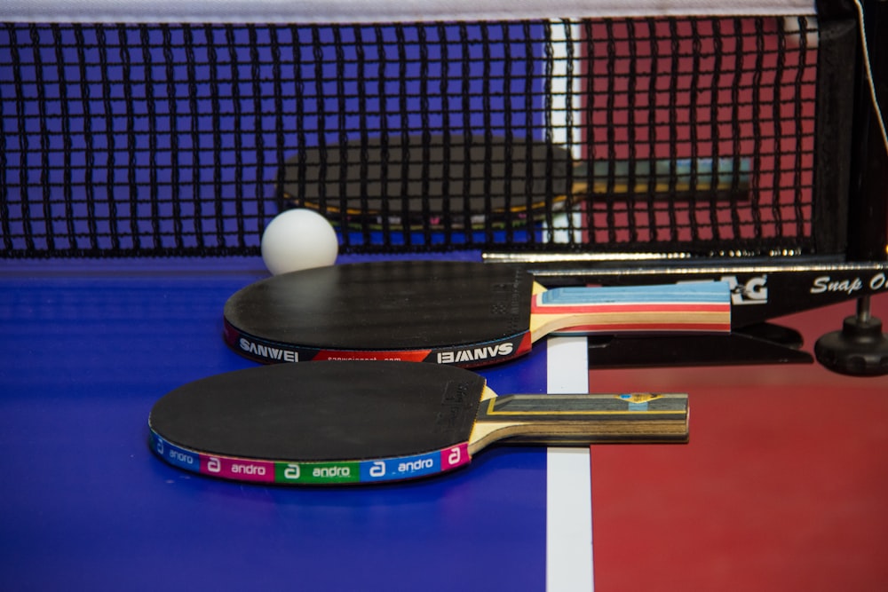 two ping pong paddles resting on a ping pong table