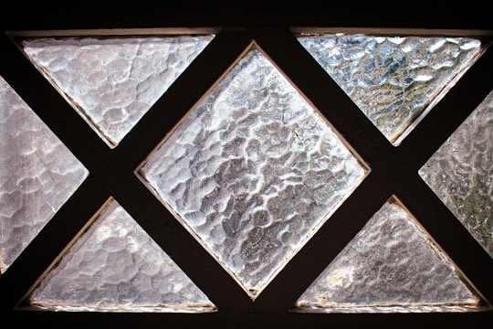 A series of textured glass panes arranged in a grid with triangular shapes, creating a pattern that allows diffused light to pass through. The glass has a rough, wavy surface that distorts the view.