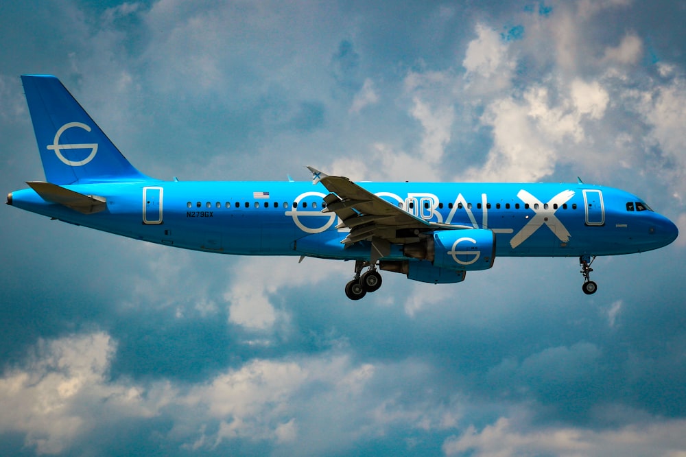 a large blue airplane flying through a cloudy sky