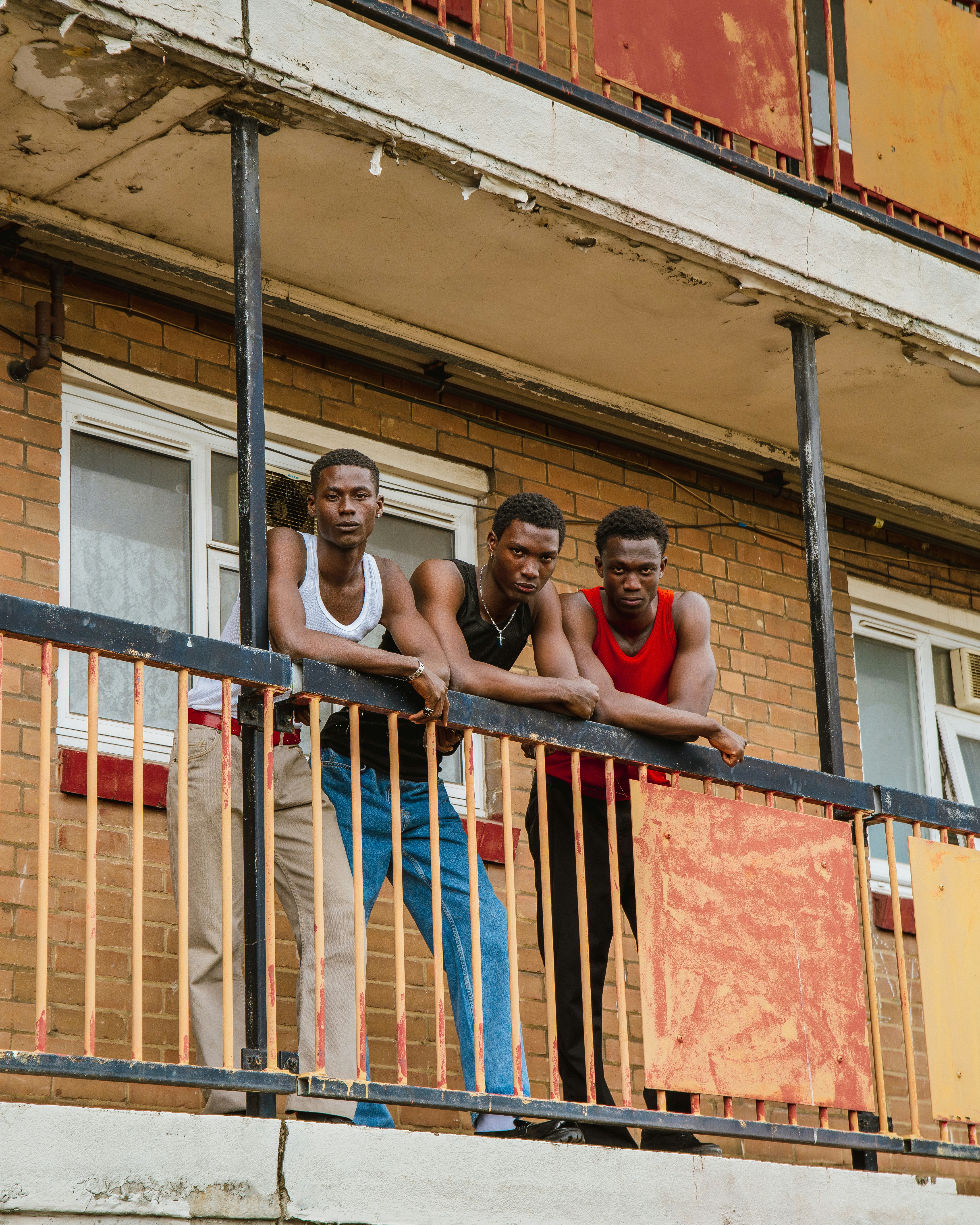 Three men standing on a balcony of a building photo – Free Portrait ...