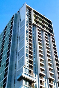 Modern residential building exterior with balconies and large windows under clear sky.