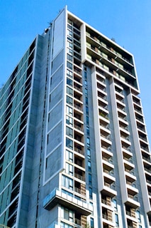 Modern residential building with balconies and large windows under a clear blue sky