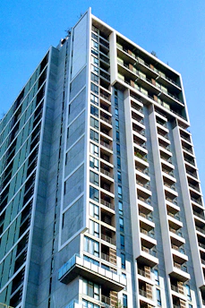 Modern, elegant residential building with spacious balconies under a clear blue sky