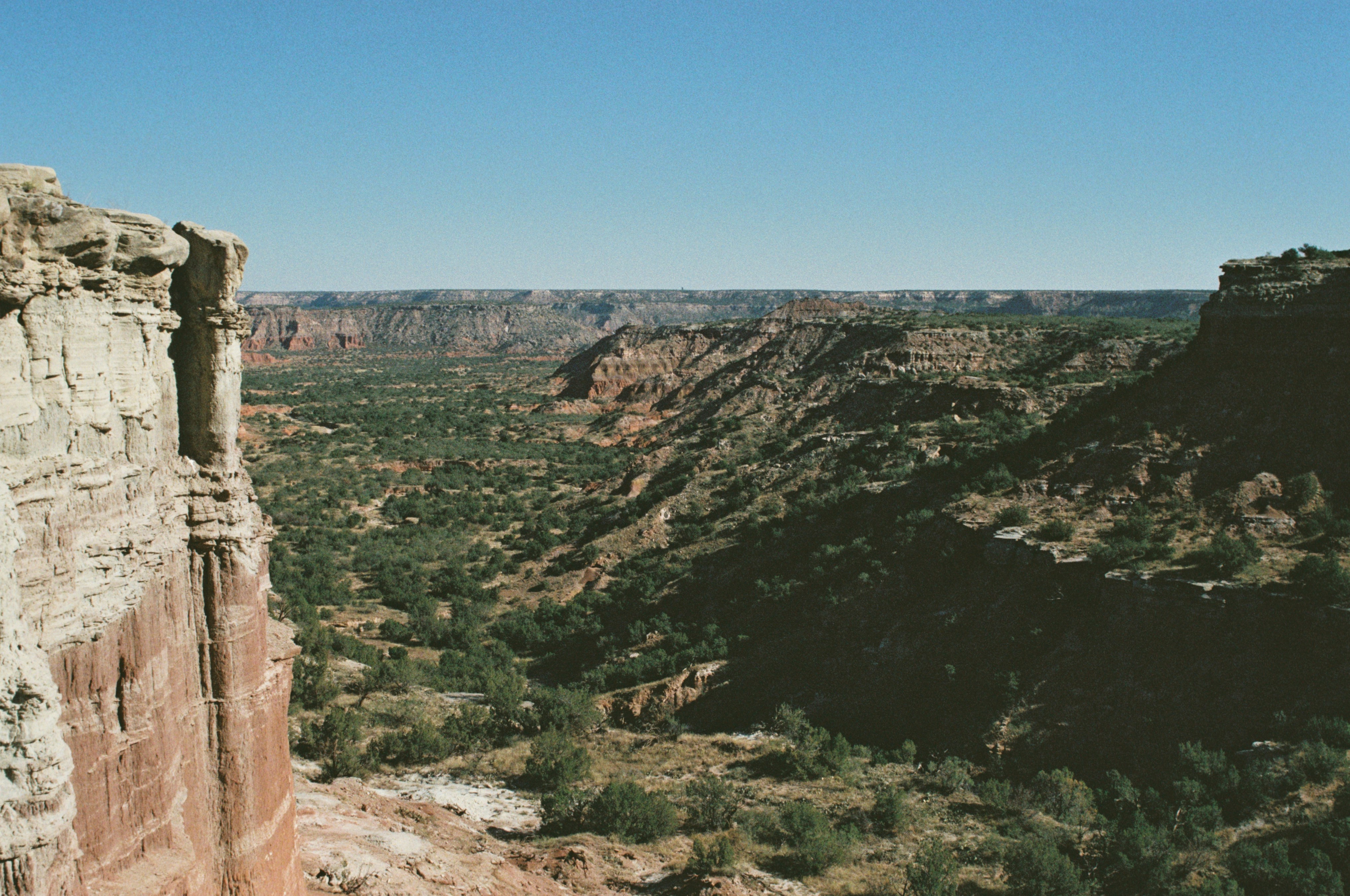a person standing on a cliff overlooking a valley, 