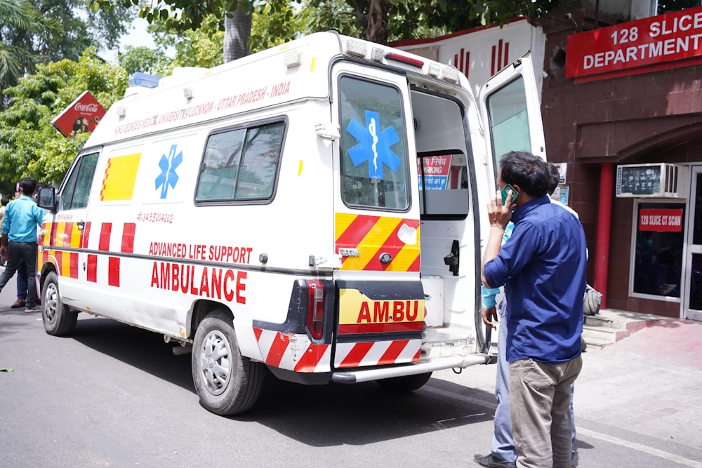 a man standing next to an ambulance parked on the side of a road