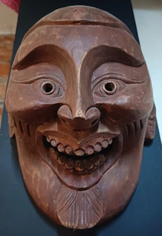 An ancient wooden mask used in traditional Malay storytelling ceremonies, worn and rich with history.