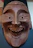 Close-up of a customer holding a finely carved wooden mask, smiling with delight.
