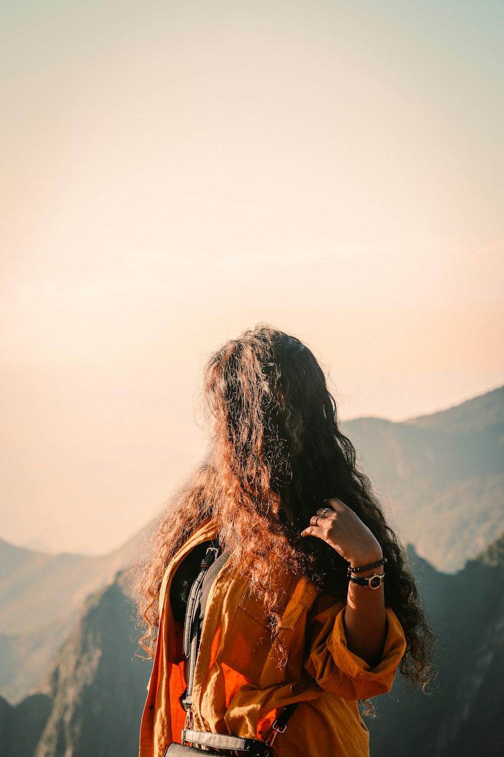 a woman with long hair standing on top of a mountain